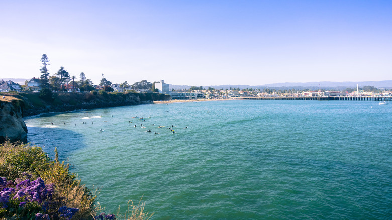 Santa Cruz's Cowell Beach on a calm day with tiny waves and surfers in the water.
