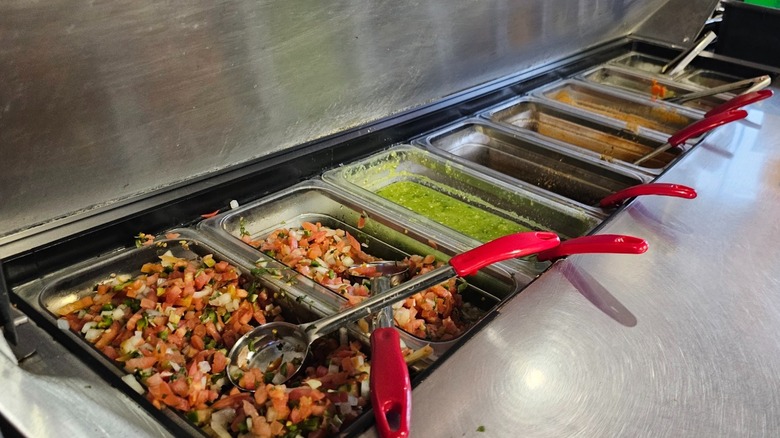 The salsa bar at Taqueria Los Pericos in Santa Cruz filled with salsa, picos, and other condiments.