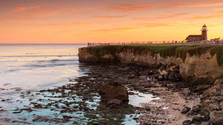 A small lighthouse stands on a cliff overlooking a rocky beach at low tide in Santa Cruz, California.