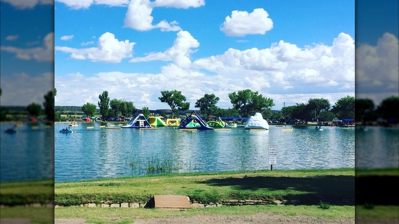 An inflatable obstacle course floats in the middle of a lake with a forested background