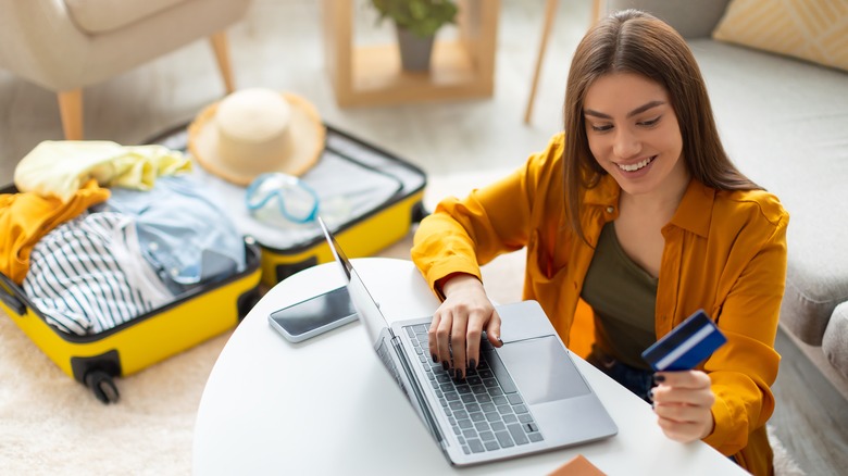A woman making a reservation on her computer and paying with a credit card
