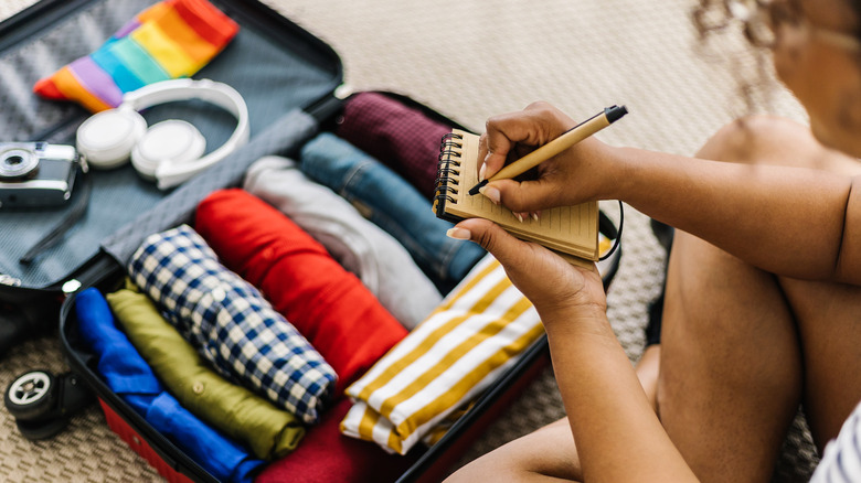 A woman carefully packing her bag and rolling her clothes to maximize space