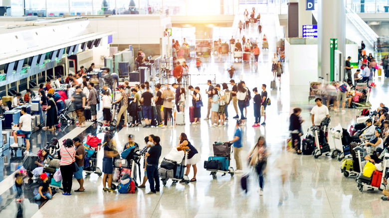 Passengers waiting in line with luggage at an airport