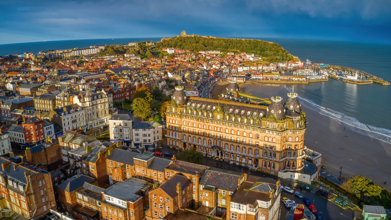 An aerial photo of Scarborough's seafront Grand Hotel in front of the sea and a castle on a leafy hill in the background