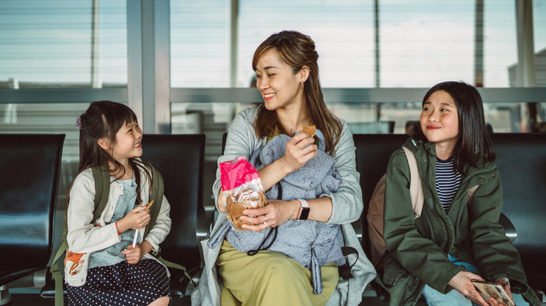 Woman and two children sitting eating snacks from a bag