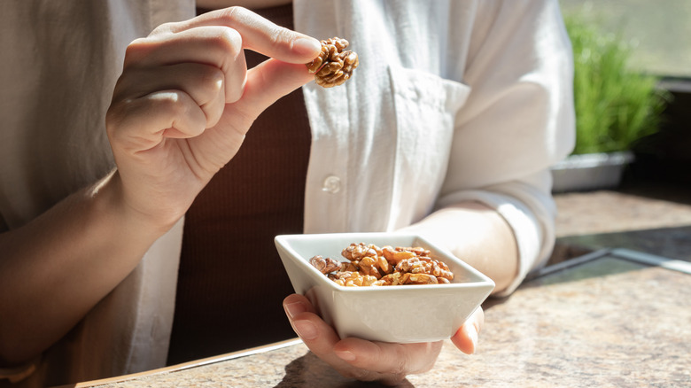 A woman picking a walnut up from a dish