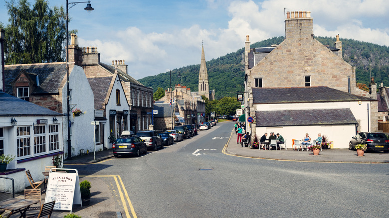 A quaint town street lined with low Victorian-style builidngs, parked cars, and shop signs