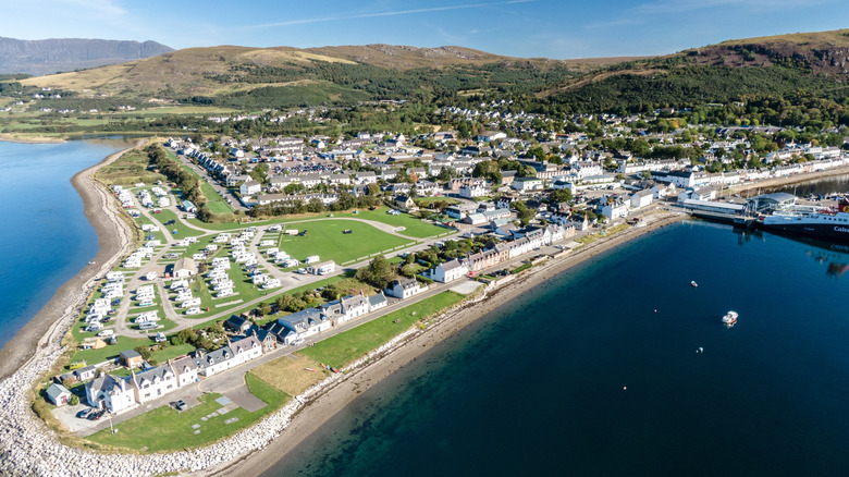 Aerial view of a harbortown with whitewashed buildings and a harbor with mountains in the distance
