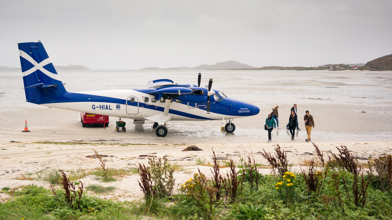 Passengers disembarking airplane on beach