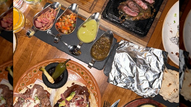 Table spread with steak, carne asada, tortillas, and salsas at Asadero