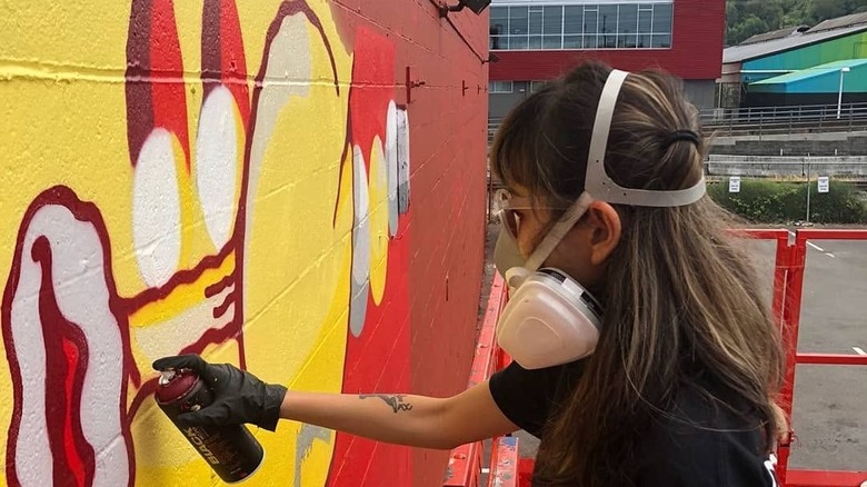 An arstist spray paints a wall in the SODO Track art project in Seattle, Washington