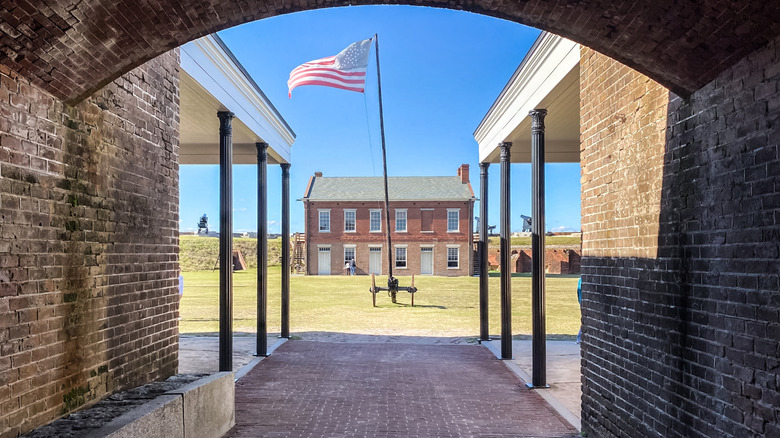 An American flag waves in the wind as the camera looks through a gap in a brick building at Fort Clinch State Park, Florida.