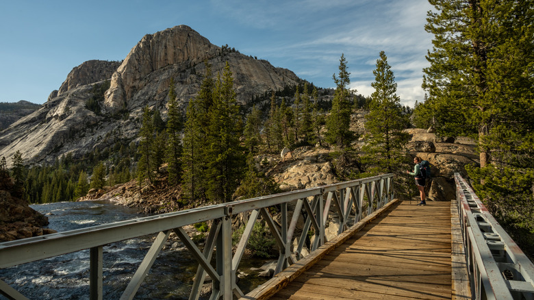 A woman hiker on the bridge to Glen Aulin High Sierra Camp at Yosemite National Park