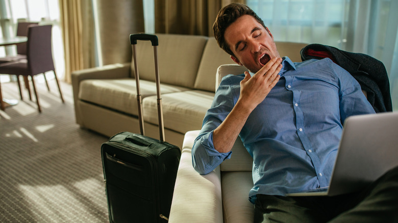 Businessman yawning in an aiport lounge.