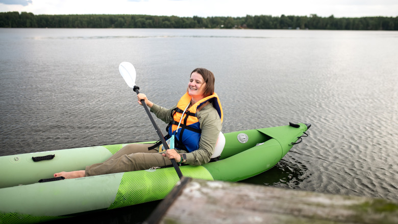 Woman in a life jacket kayaking on a lake