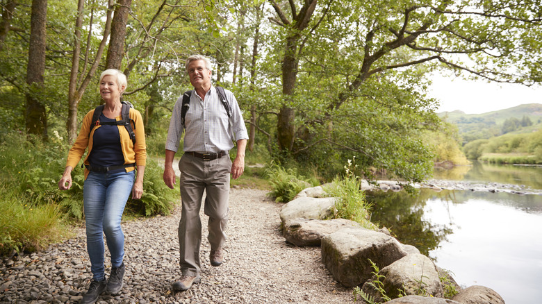 A happy senior couple hike along a forested path at a national park.