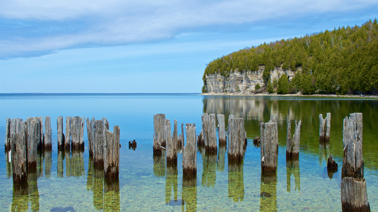 Wooden stilts in the lake with limestone cliffs in background