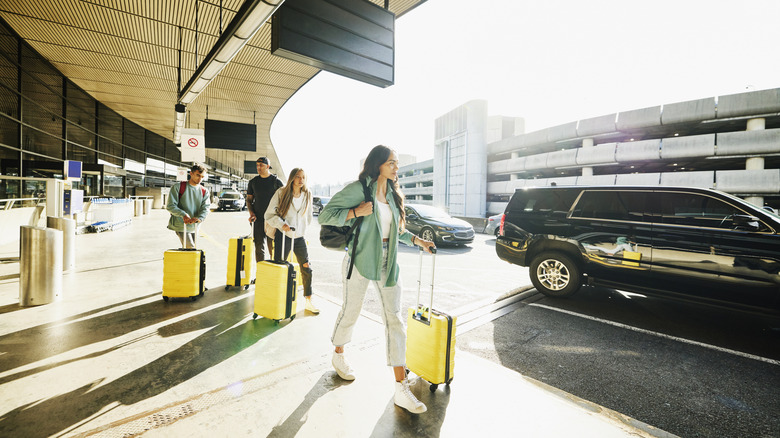 Travelers with yellow suitcases outside an airport