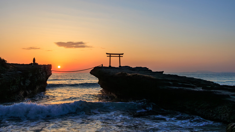 Silhouette of a torii stands on a rock at sea at sunset in Shimoda, Japan