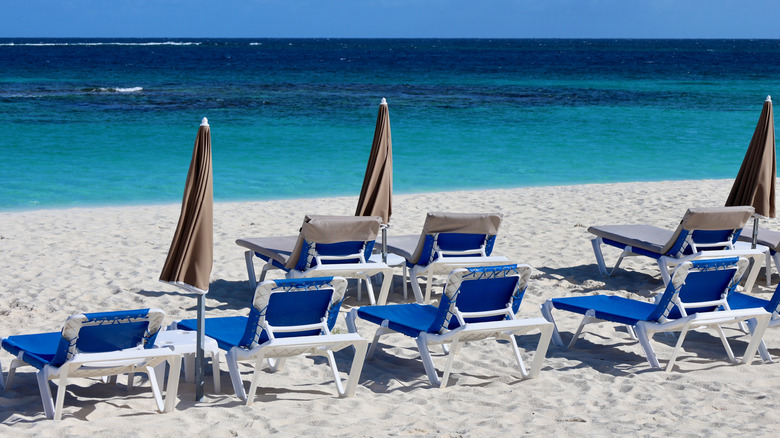 Empty beach loungers on the white sand at Shoal Bay East beach.