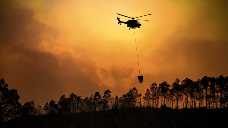 Helicopter carrying water bucket over fire