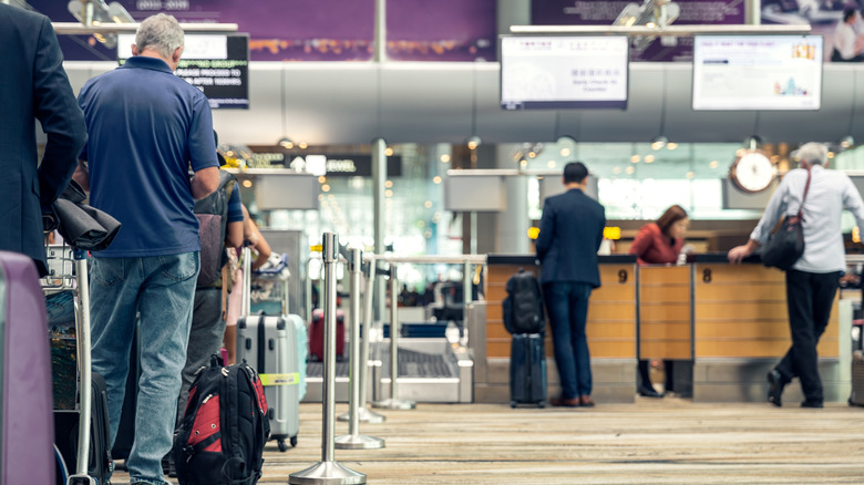 passengers lined up at airline checked baggage counter