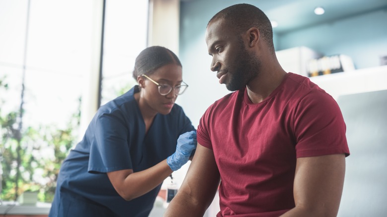 Man getting a vaccine from a medical professional in an office