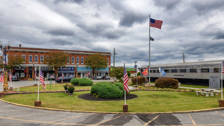 Circle Park, a small circular greenspace with several American flags framing it is pictured with Sweetwater Main Street in the background in Sweetwater, Tennessee.