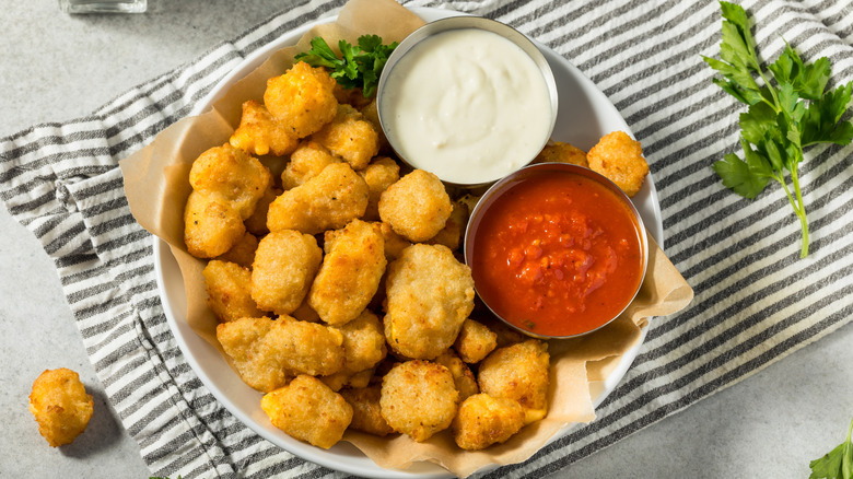 Homemade Wisconsin cheese curds on a plate with red sauce and aioli.