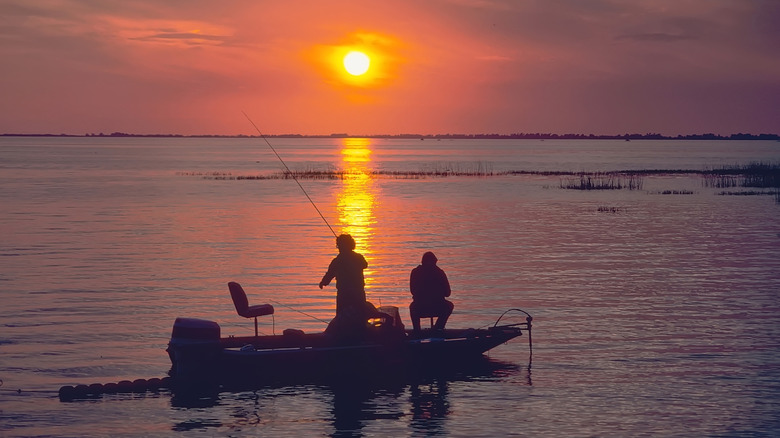 Two people fishing on boat, Lake Okeechobee, Florida at sunset