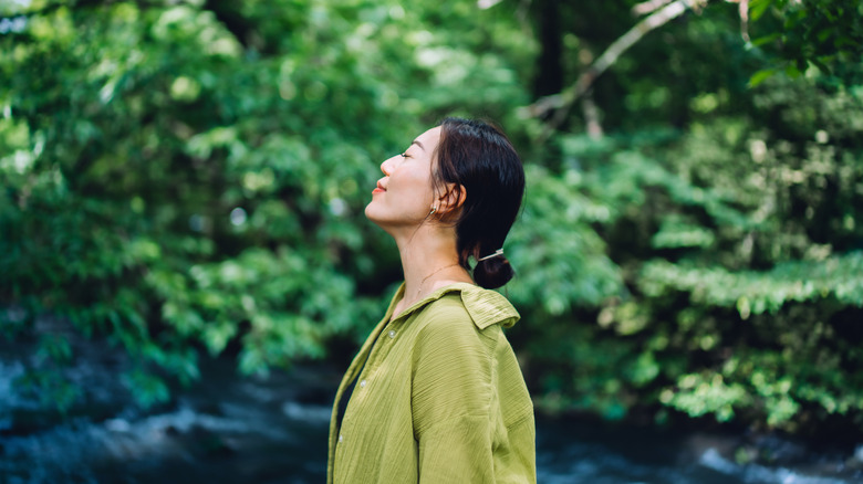 A woman surrounded by greenery looking peaceful