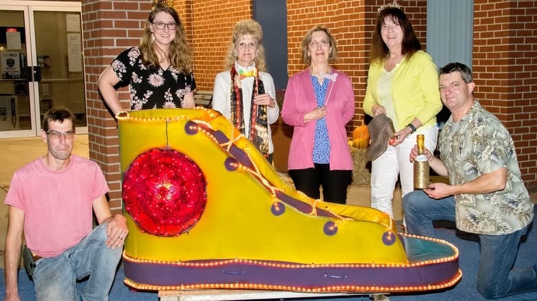 Several people standing around a bright gold and purple Converse show covered in lights