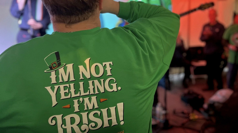 Photo of a man watching a Celtic band wearing a green Irish slogan shirt