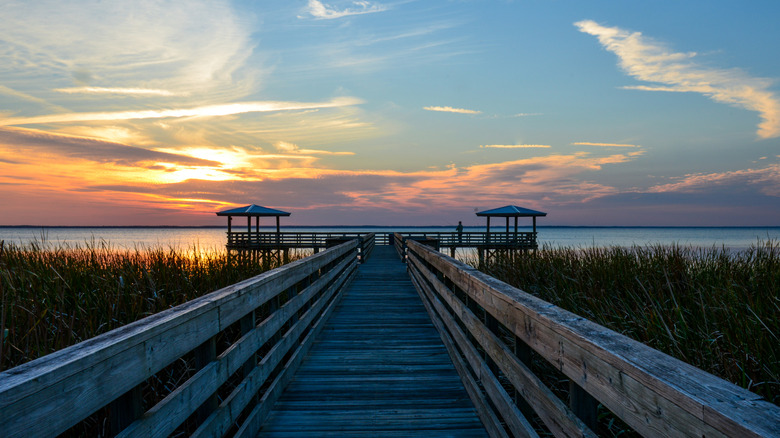 A wooden pier extends into the water at Lake George, in Florida, during sunset.