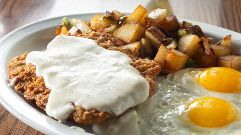 Plated fried chicken with eggs and potatoes