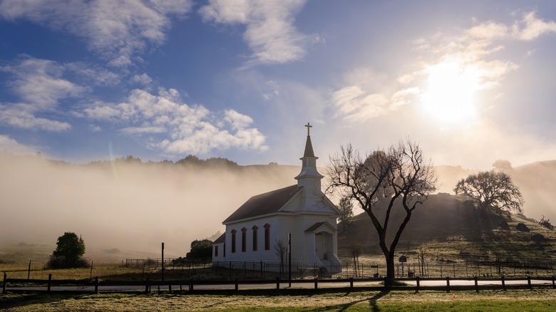 Sun shining over Old St. Mary's Church in Nicasio Valley with fog covering the background.