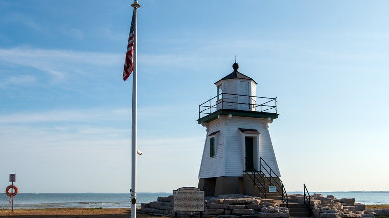 lighthouse by water and american flag