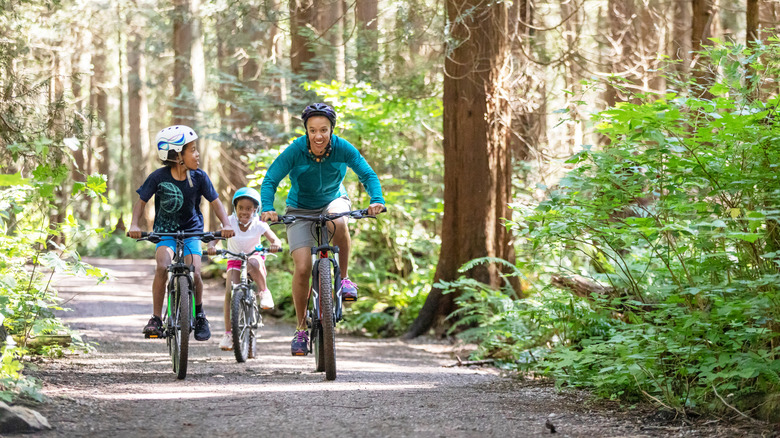 Father and two daughters cycling in woods