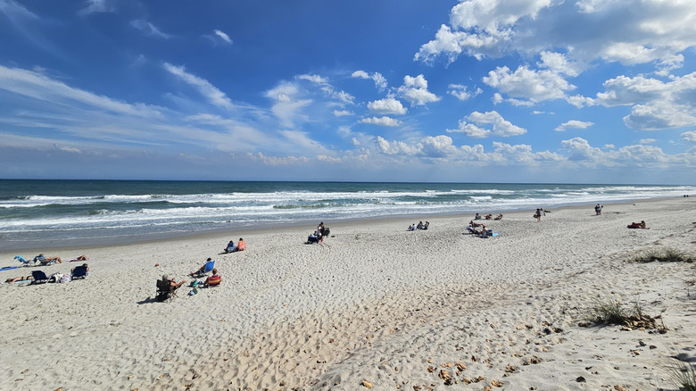 People sunbathing on the white sands at Bicentennial Beach Park in Indian Harbour Beach, Florida