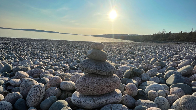 Smooth pebbles covering the shore of Schreiber Beach with Lake Superior and trees in the background.