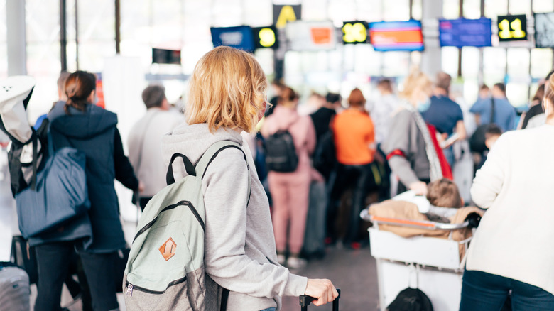 woman looks at long airport security lines