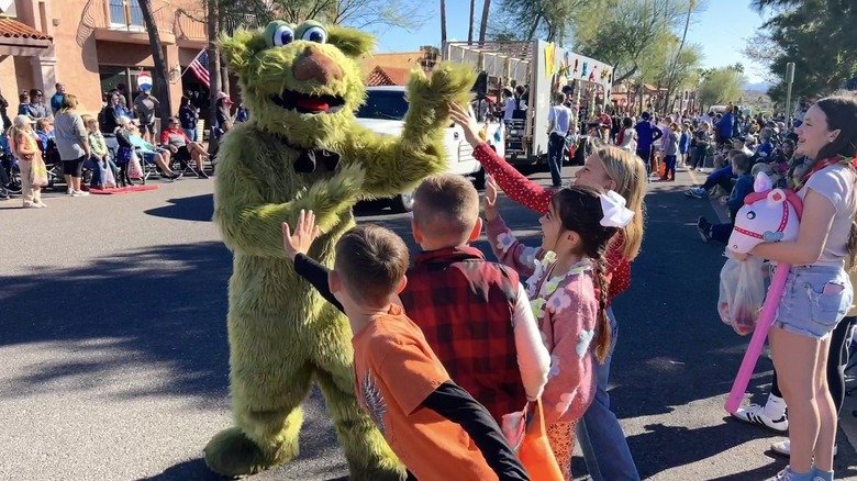 A character costume high-fives children in parade
