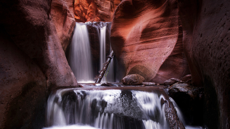 Waterfall inside slot canyon with ladder leading up in Kanarra Falls