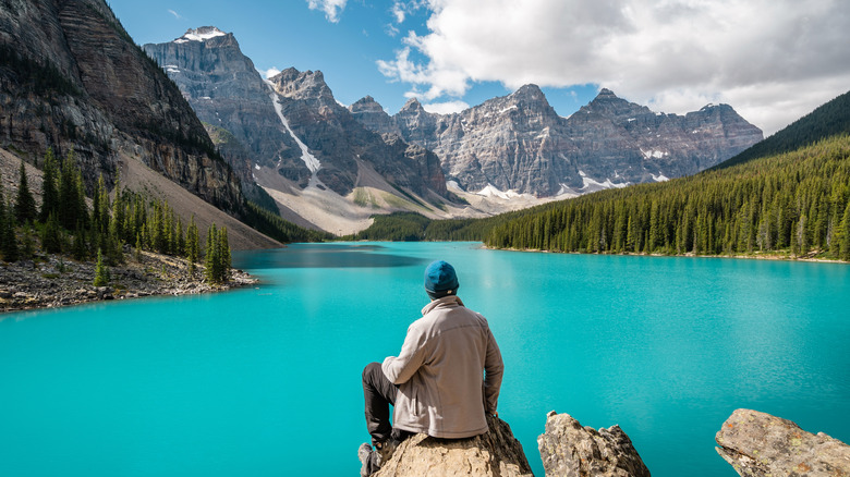 Person sitting on a rock overlooking a lake at Banff National Park in Alberta, Canada