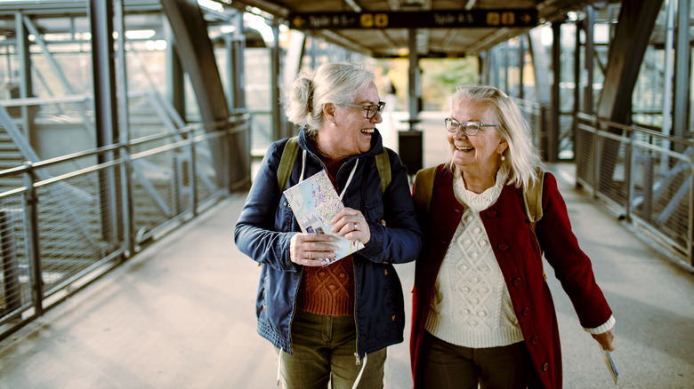 Two mature woman walking through an airport and smiling
