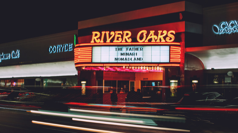 yellow neon sign on marquee over movie theatre on street
