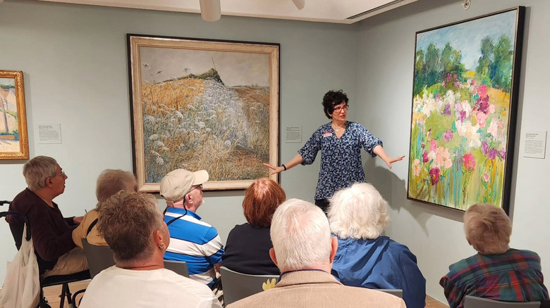 Woman presents paintings to a group of people at the Brandywine Museum of Art