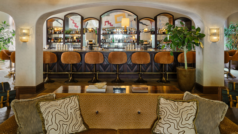 Interior of the main bar, with rows of alcohol and plush bar seats visible, at Soho House São Paulo, a members-only club located in Brazil