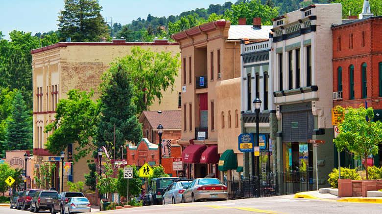 View of Main Street in Manitou Springs, Colorado from the top of the hill overlooking trees, buildings, and parked cars