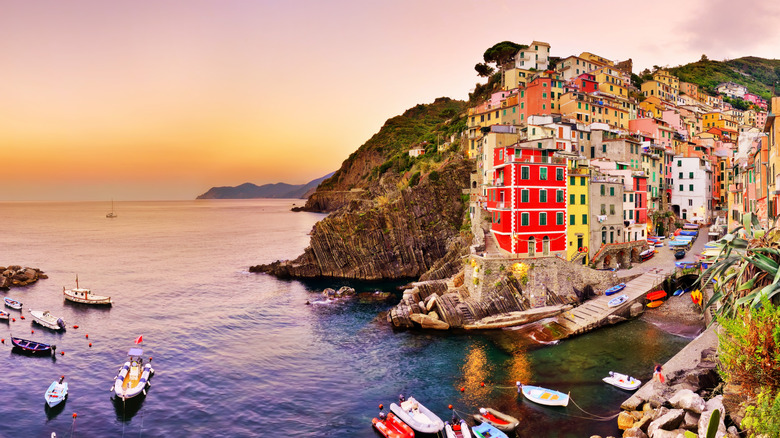 View of Cinque Terre's pastel-hued buildings on a cliff and boats on the sea